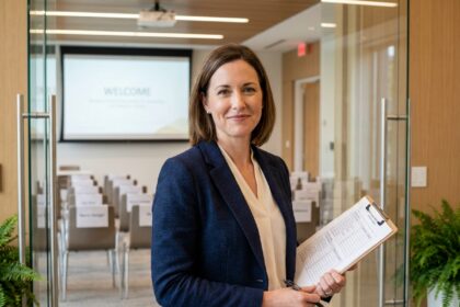 Coordinatrice tenant une check-list devant une salle de séminaire organisée avec chaises et écran de projection